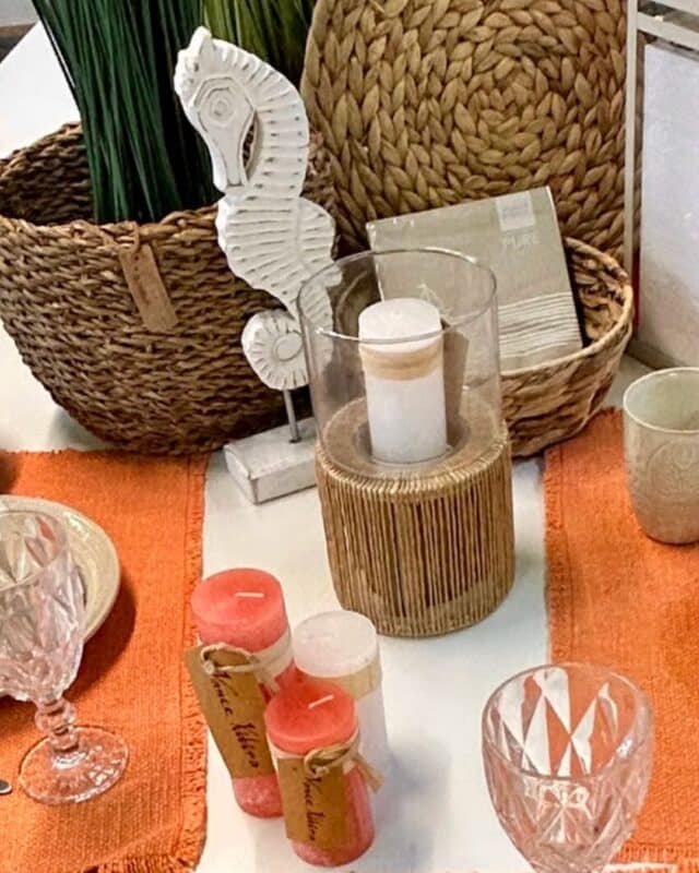 Orangene mediterrane Kerzen und Windlichter auf einem schön dekorierten Esstisch.